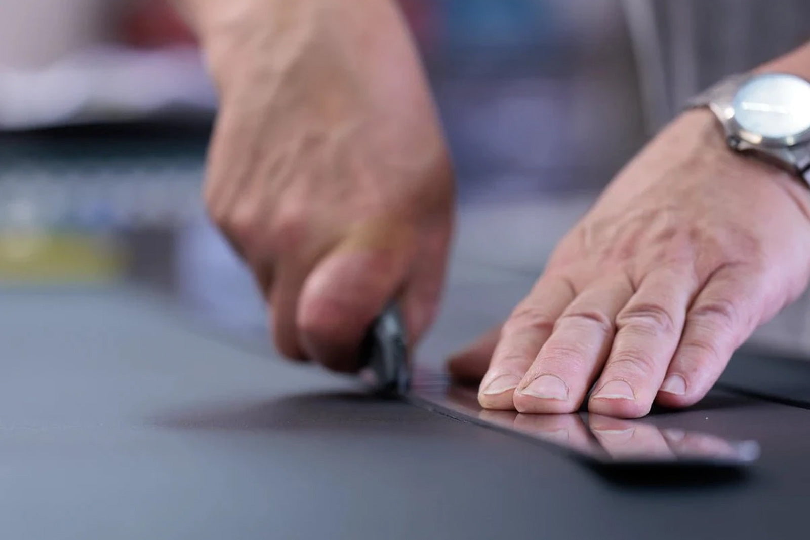 Découpe manuelle d’un panneau de cuir au couteau le long d’une règle métallique