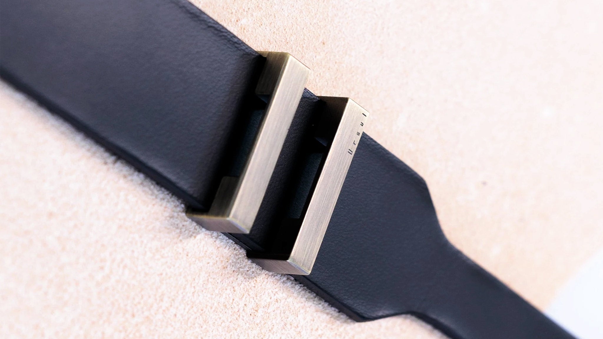 Boucle métal Ursul posée sur lanière de cuir noir, gros plan de la matière